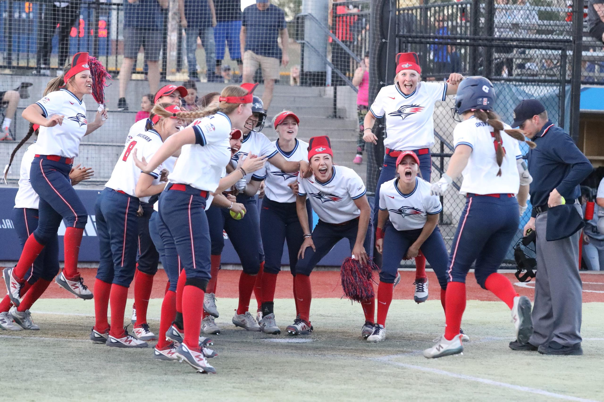 垒球 player Shelby Robb approaches home plate after a walk-off home run as her teammates enthusiastically wait to greet her.